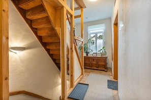 A wooden staircase leading to a landing with a view of a window and a plant.