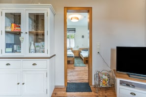 A room with a white cabinet, a television, and a bed with a wooden floor.