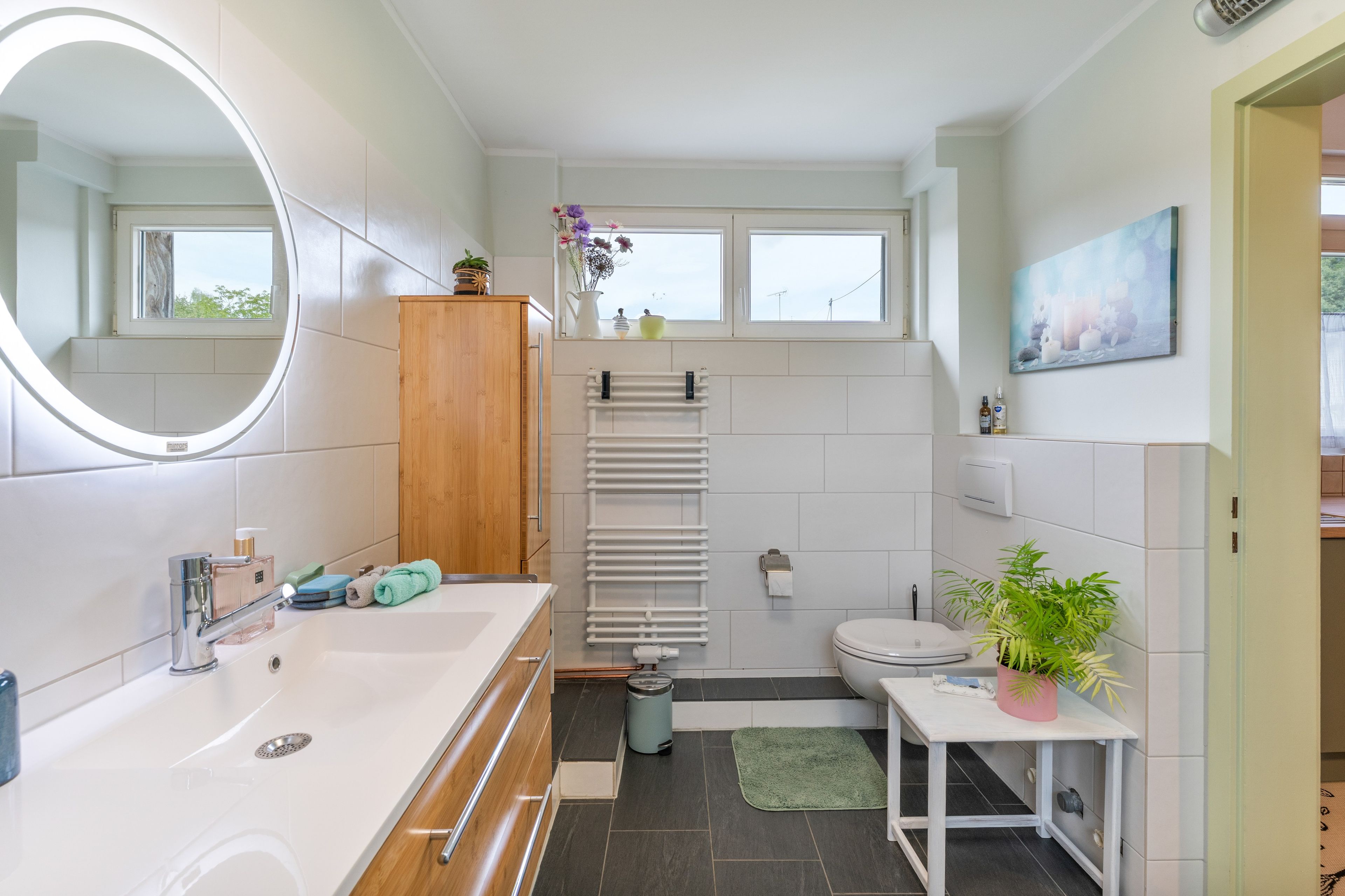 A modern bathroom with a large mirror, a bathtub, a toilet, and a sink.