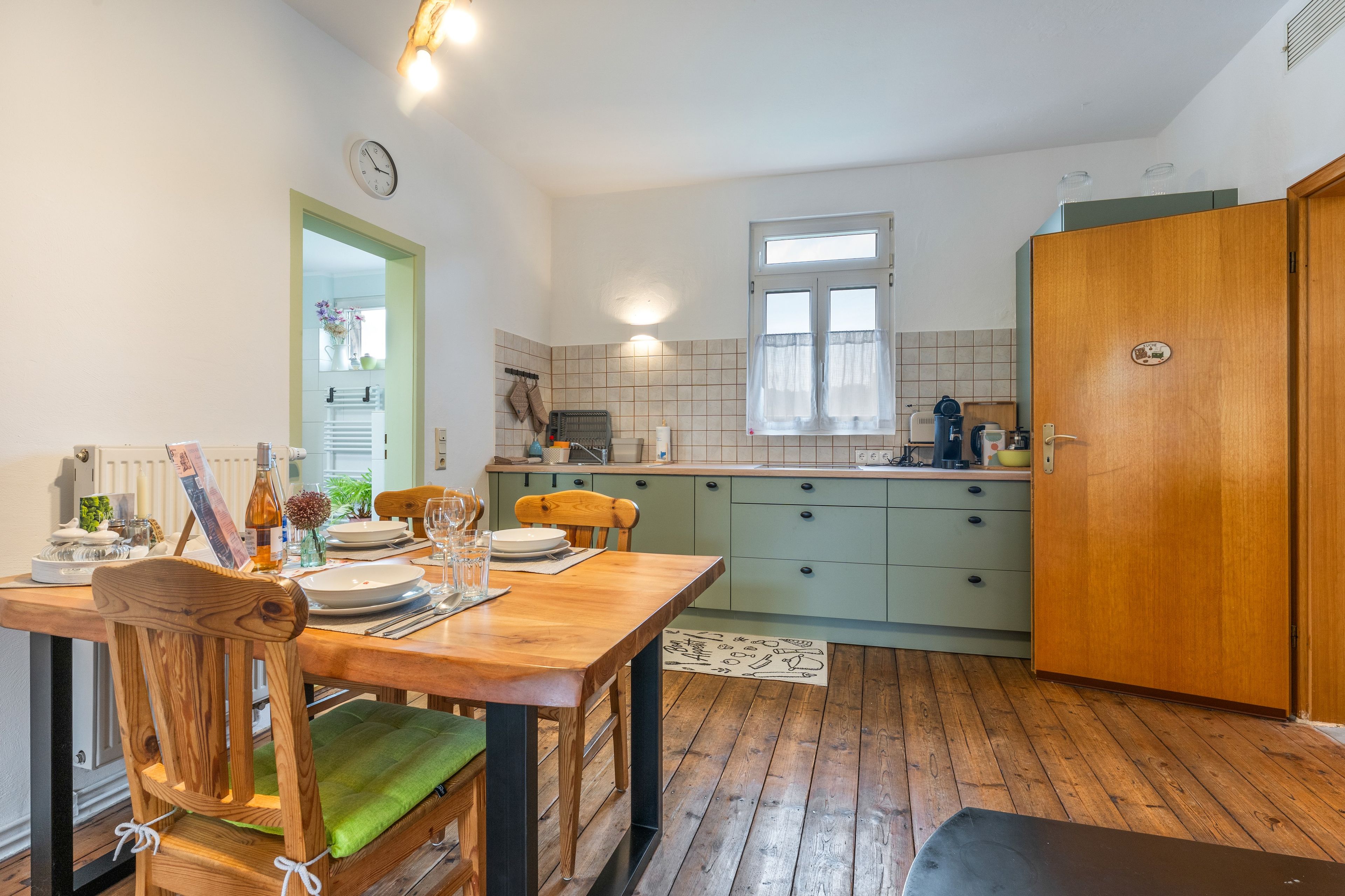 Una cocina compacta con comedor, muebles de madera y una ventana con cortinas.