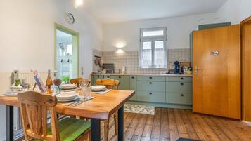 Una cocina compacta con comedor, muebles de madera y una ventana con cortinas.