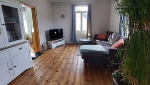 Ein Wohnzimmer mit Fernseher, Sofa und Schrank.