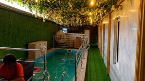 Una piscina interior con piso de césped artificial verde, rodeada por una plataforma de metal con barandillas.
