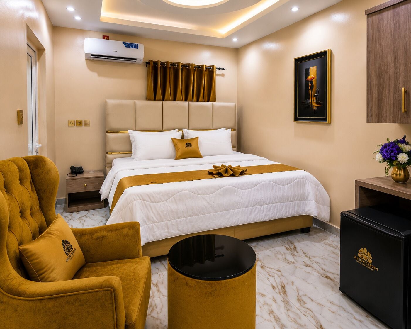 Ein Hotelzimmer mit Bett, Sessel, Nachttisch, Klimaanlage, Gemälde und Schrank.