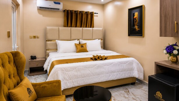 Habitación de hotel con cama, una silla, mesita de noche, equipo de aire acondicionado, un cuadro y un armario.