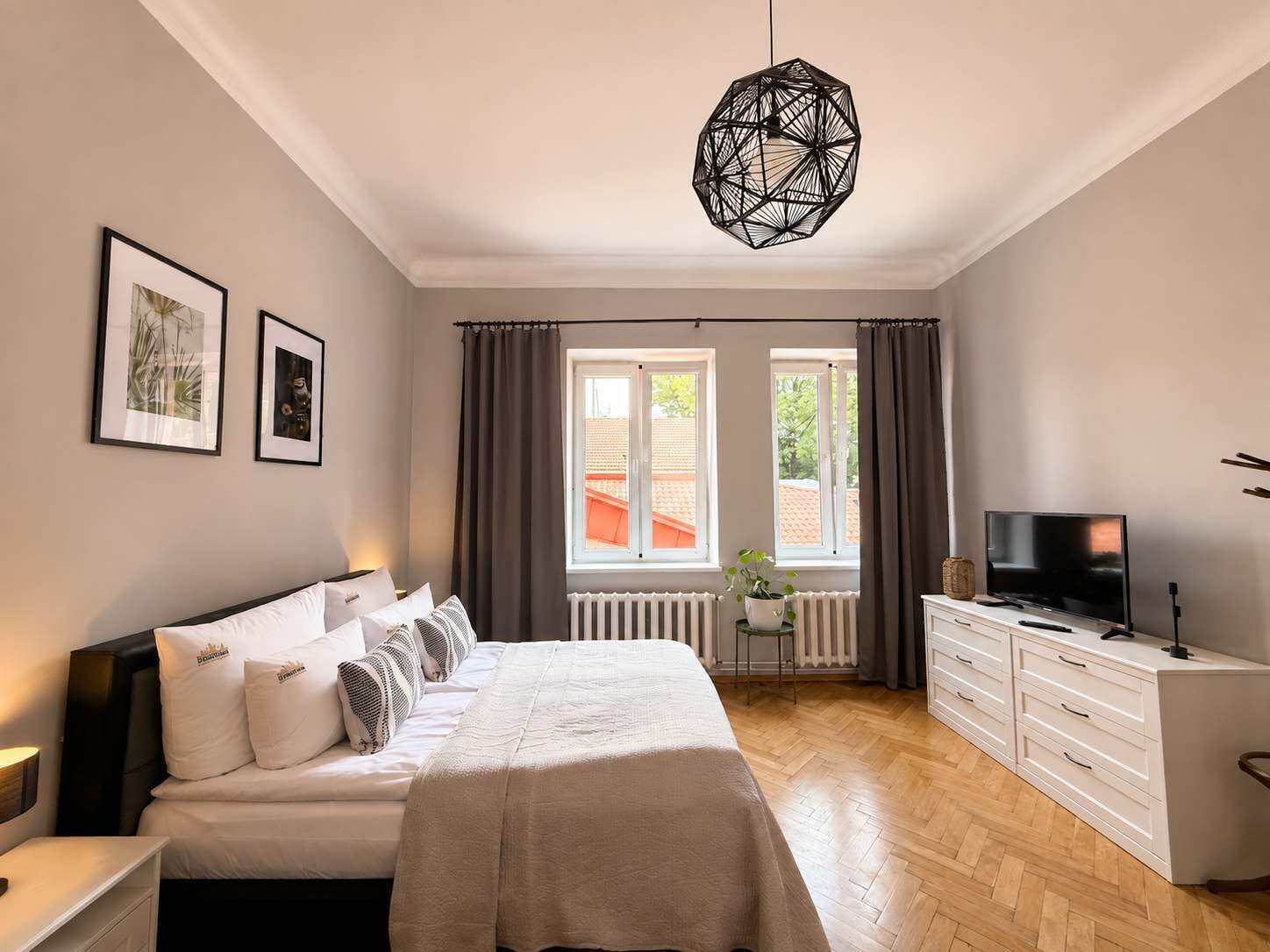 Una camera da letto con un letto, una TV, un comò e una finestra con tende.