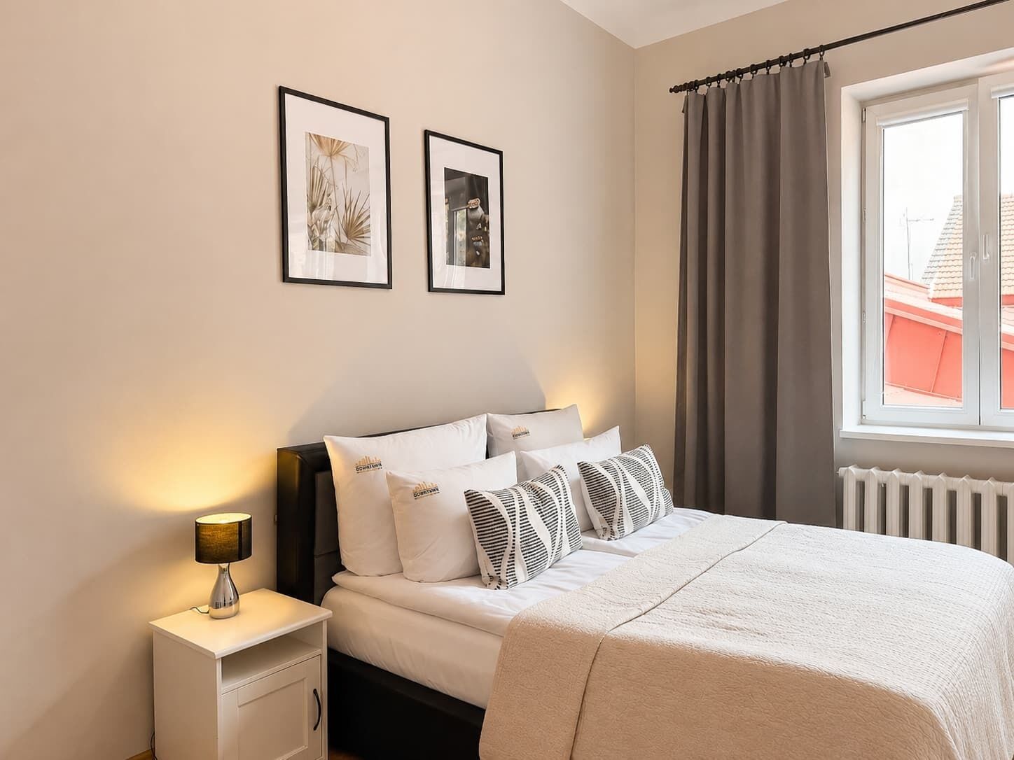 Una camera da letto con un letto, un comodino, una lampada e due quadri appesi al muro.