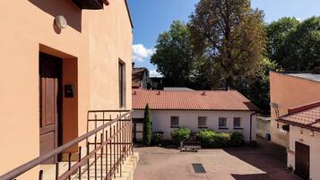 A courtyard with a paved walkway, a wooden door, and a metal railing.