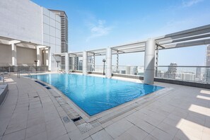 Una piscina sul tetto con acqua cristallina, circondata da un solarium in piastrelle bianche e elementi architettonici moderni.