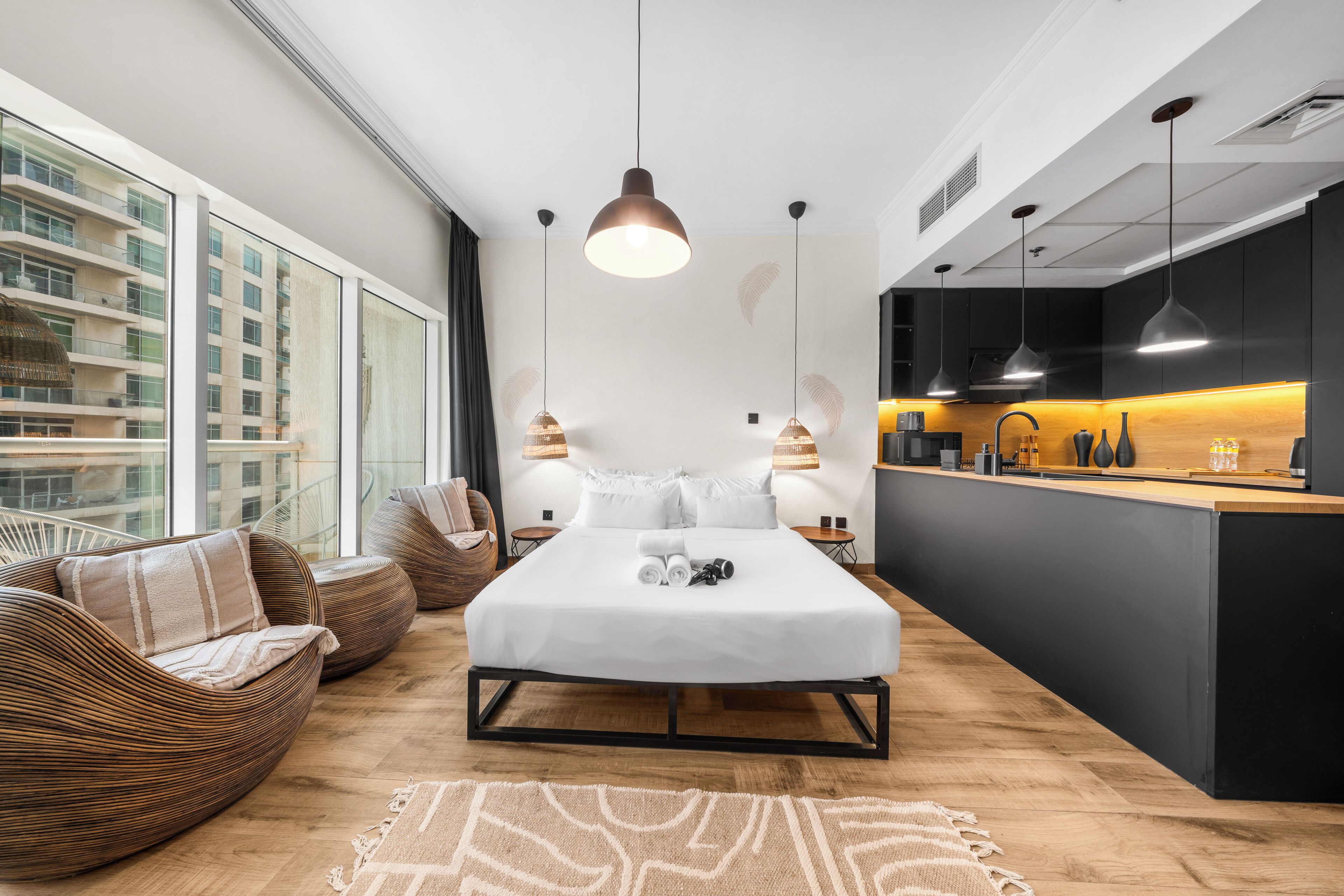 Una habitación de hotel moderna con una cama grande, un sofá, una zona de comedor y vistas a la ciudad.