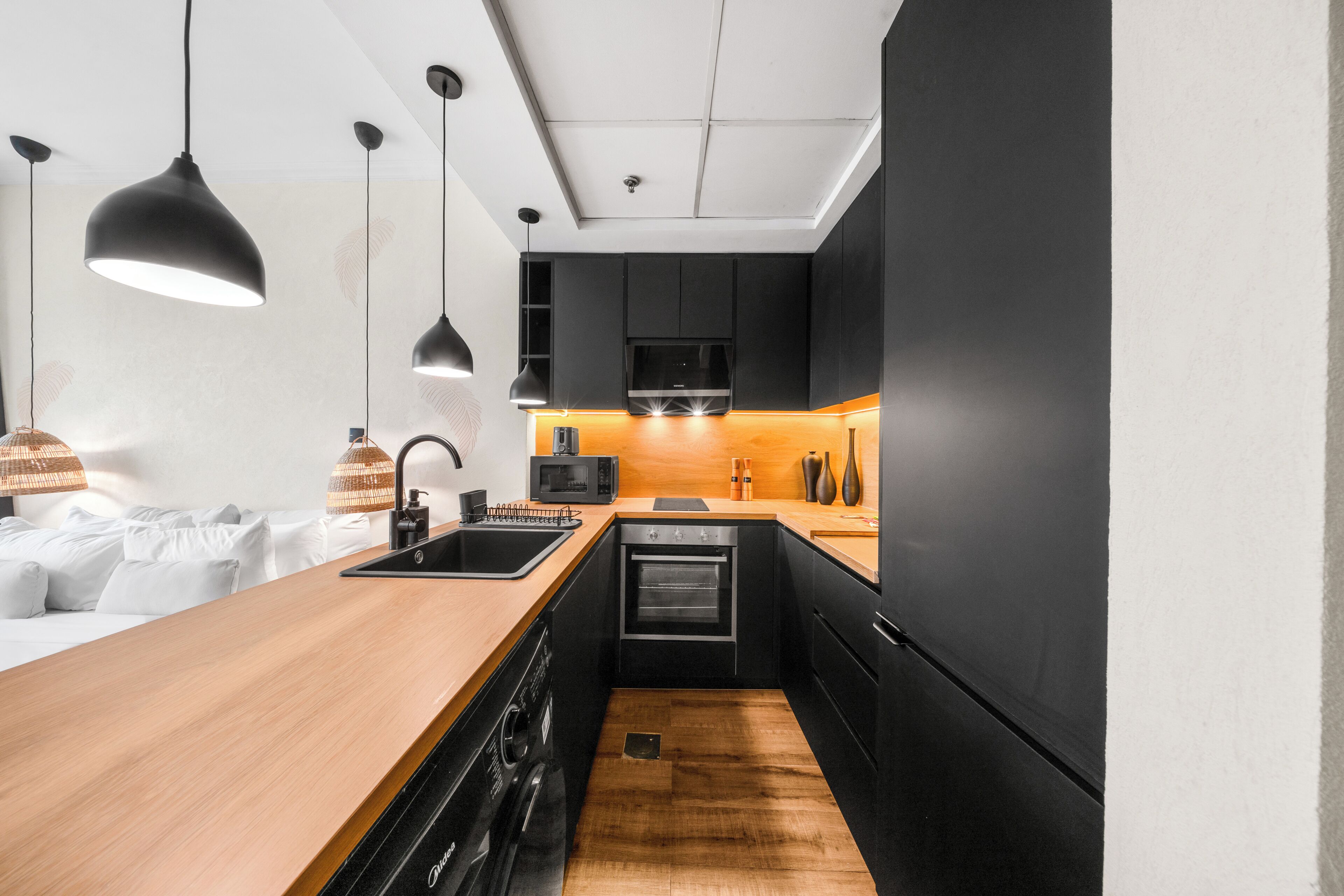 Een moderne keuken met een houten aanrechtblad, zwarte apparaten en hanglampen.