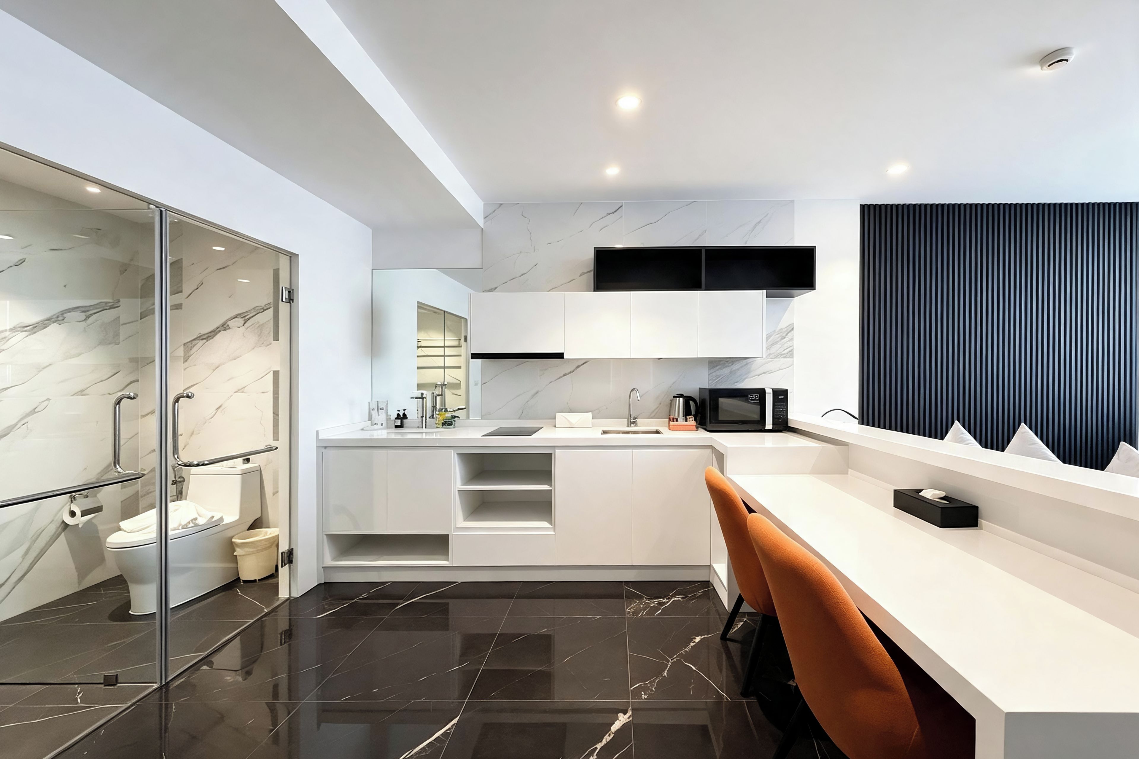 A modern kitchen with a marble backsplash, a built-in microwave, and a black countertop.