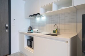 A modern kitchen with white cabinetry, a stainless steel sink, and a built-in oven. - Utopia Dream U2 Prestige Suites & Pool (Mueang Phuket)