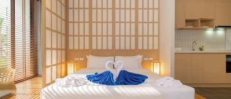 A hotel room with a large bed, a view of the outside, and a kitchen area.