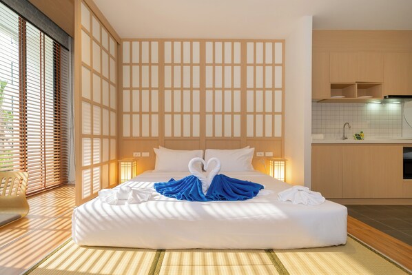 A hotel room with a large bed, a view of the outside, and a kitchen area. - Utopia Dream U2 Prestige Suites & Pool (Mueang Phuket)