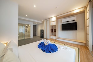 Habitación de hotel con cama, armario, televisor integrado y minibar.