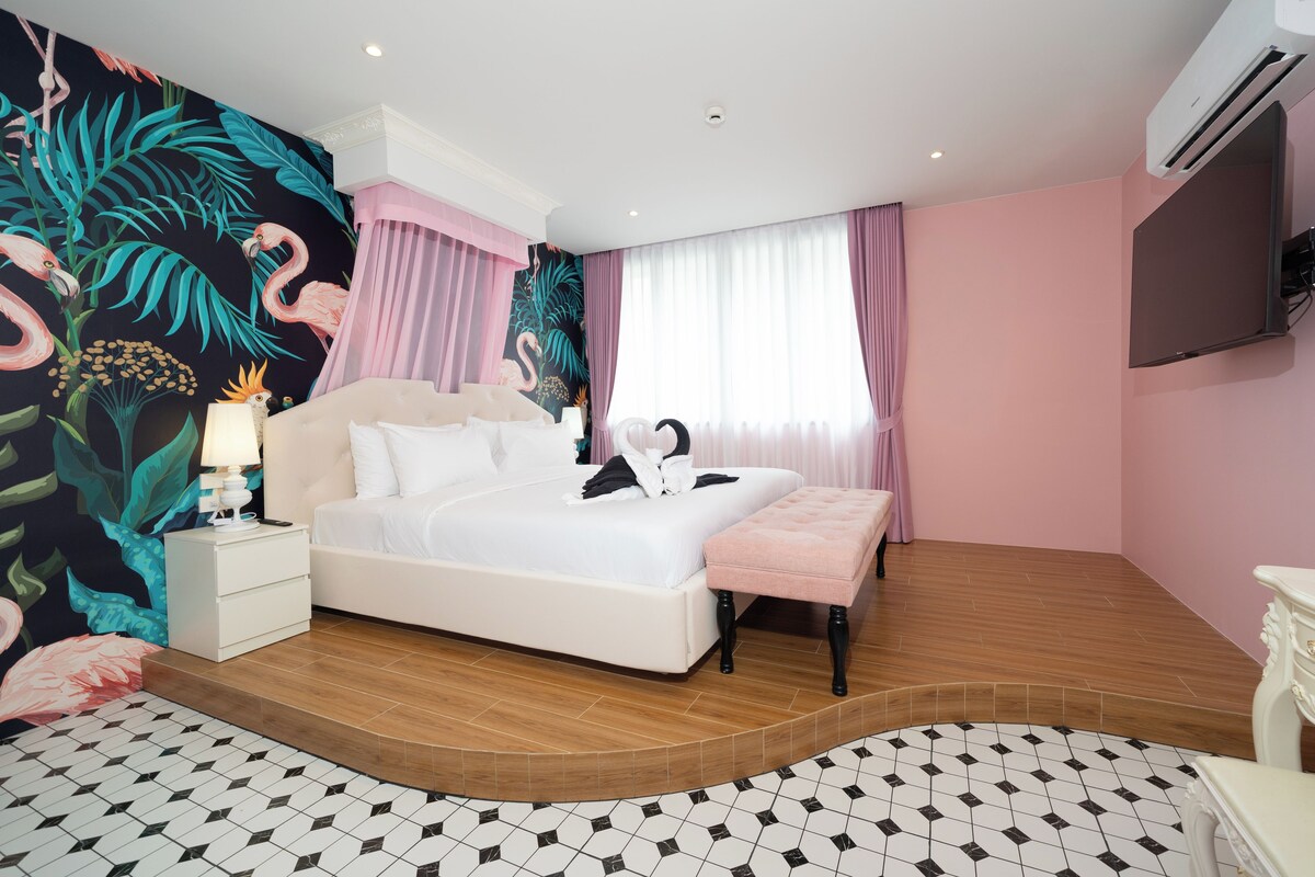 A hotel room with a bed, bedside table, lamp, and a wall mural.