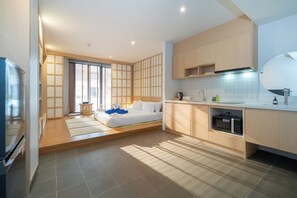 Una habitación de hotel moderna con cama, kitchenette y televisión.