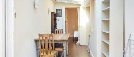 A narrow hallway with a wooden dining table and chairs, a white radiator, and a glass ceiling.