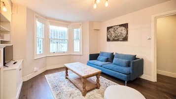 A living room with a blue sofa, a wooden coffee table, a patterned rug, and a globe artwork on the wall.