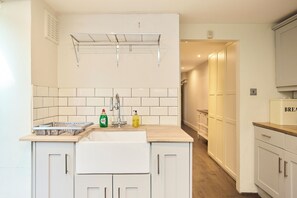 A kitchen with a sink, drying rack, and cabinets. - A Battersea State of Mind (London)