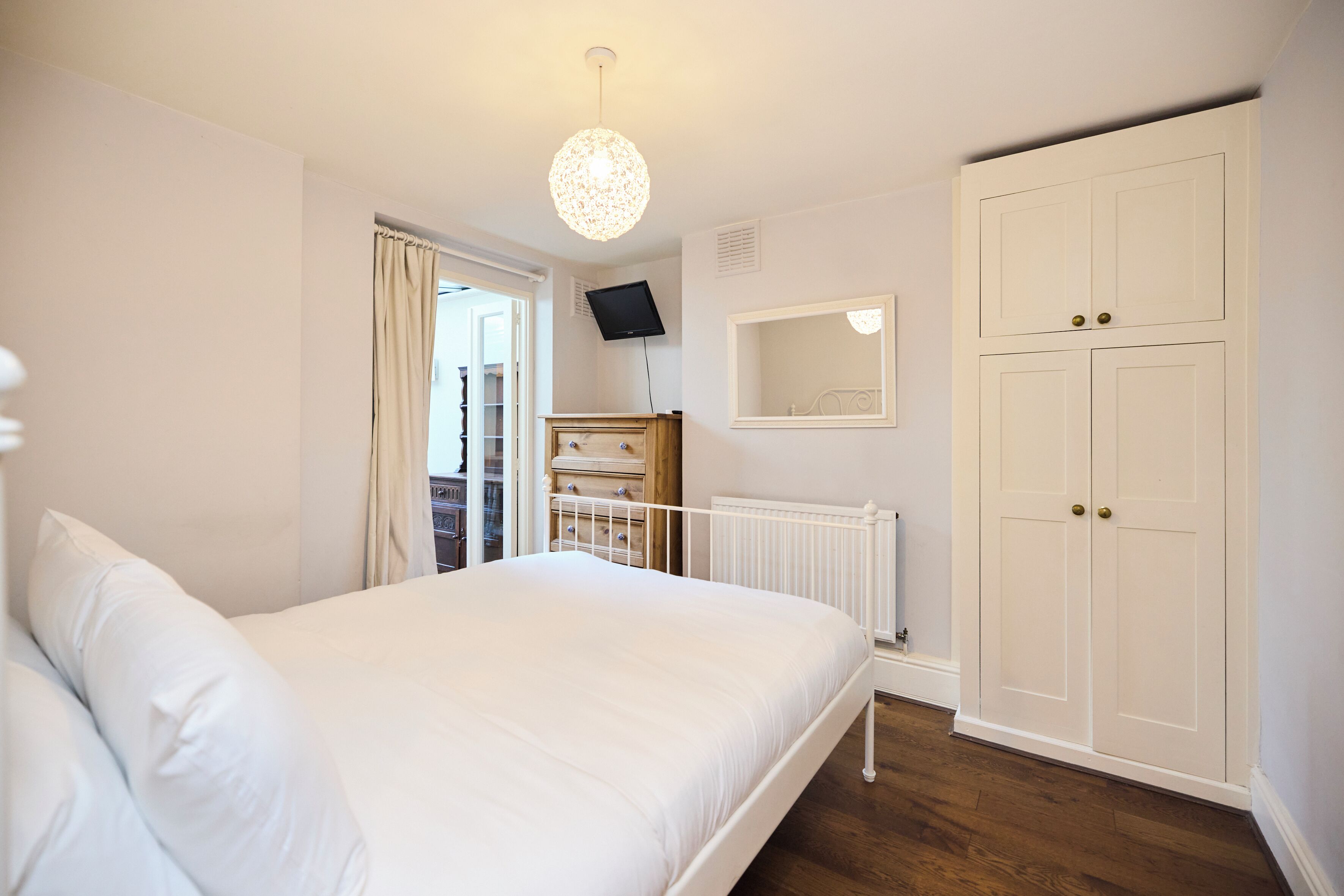 A bedroom with a bed, a wardrobe, a television, and a window.