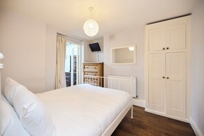 A bedroom with a bed, a wardrobe, a television, and a window. - A Battersea State of Mind (London)