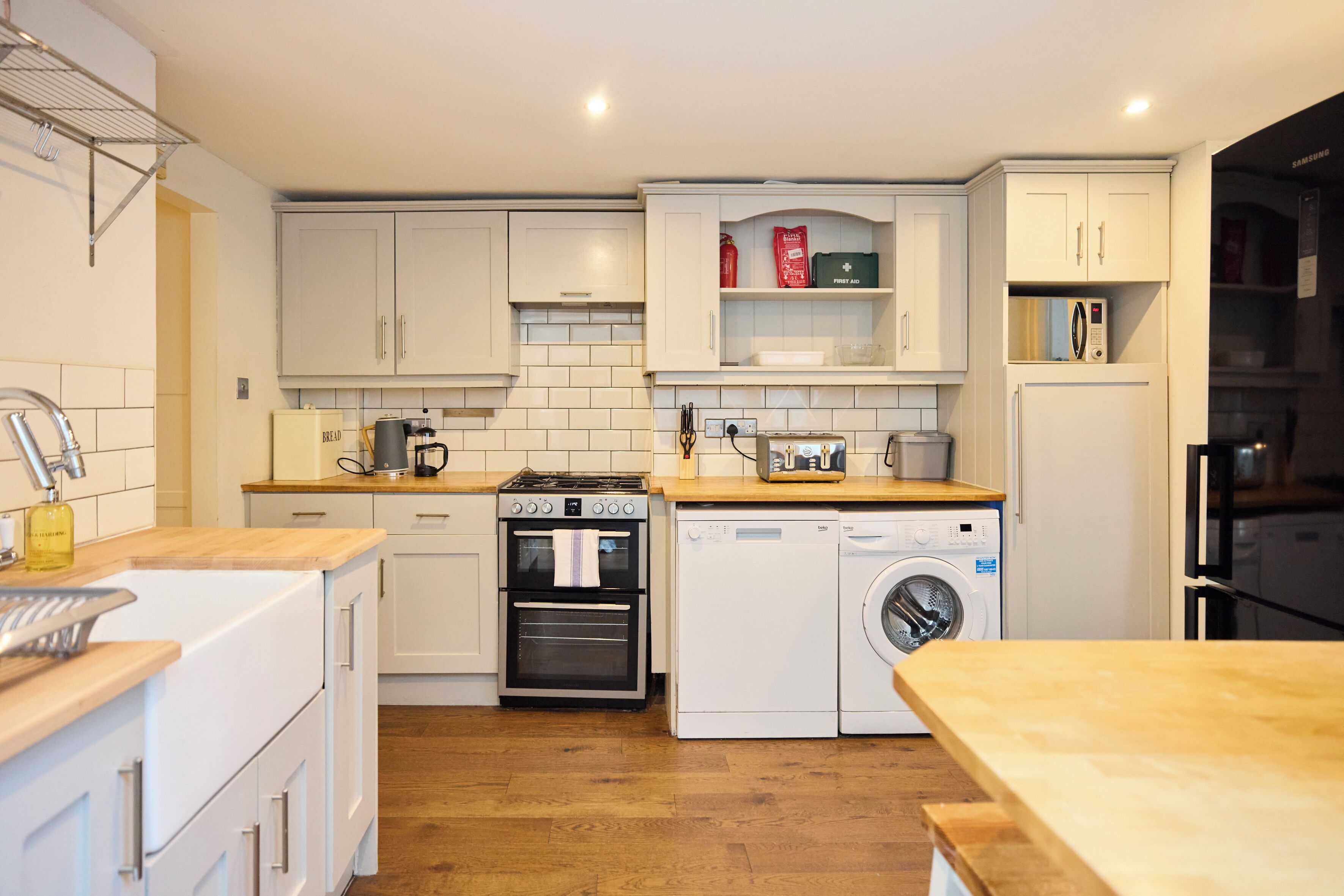 A modern kitchen with white cabinetry, a built-in oven, a microwave, and a washing machine.