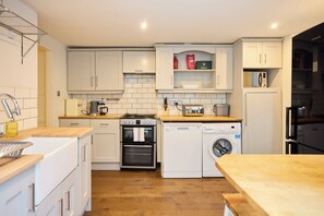 A modern kitchen with white cabinetry, a built-in oven, a microwave, and a washing machine. - A Battersea State of Mind (London)