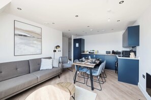 Eine moderne Wohnung mit grauem Sofa, einem Esstisch und einer Küchenzeile.