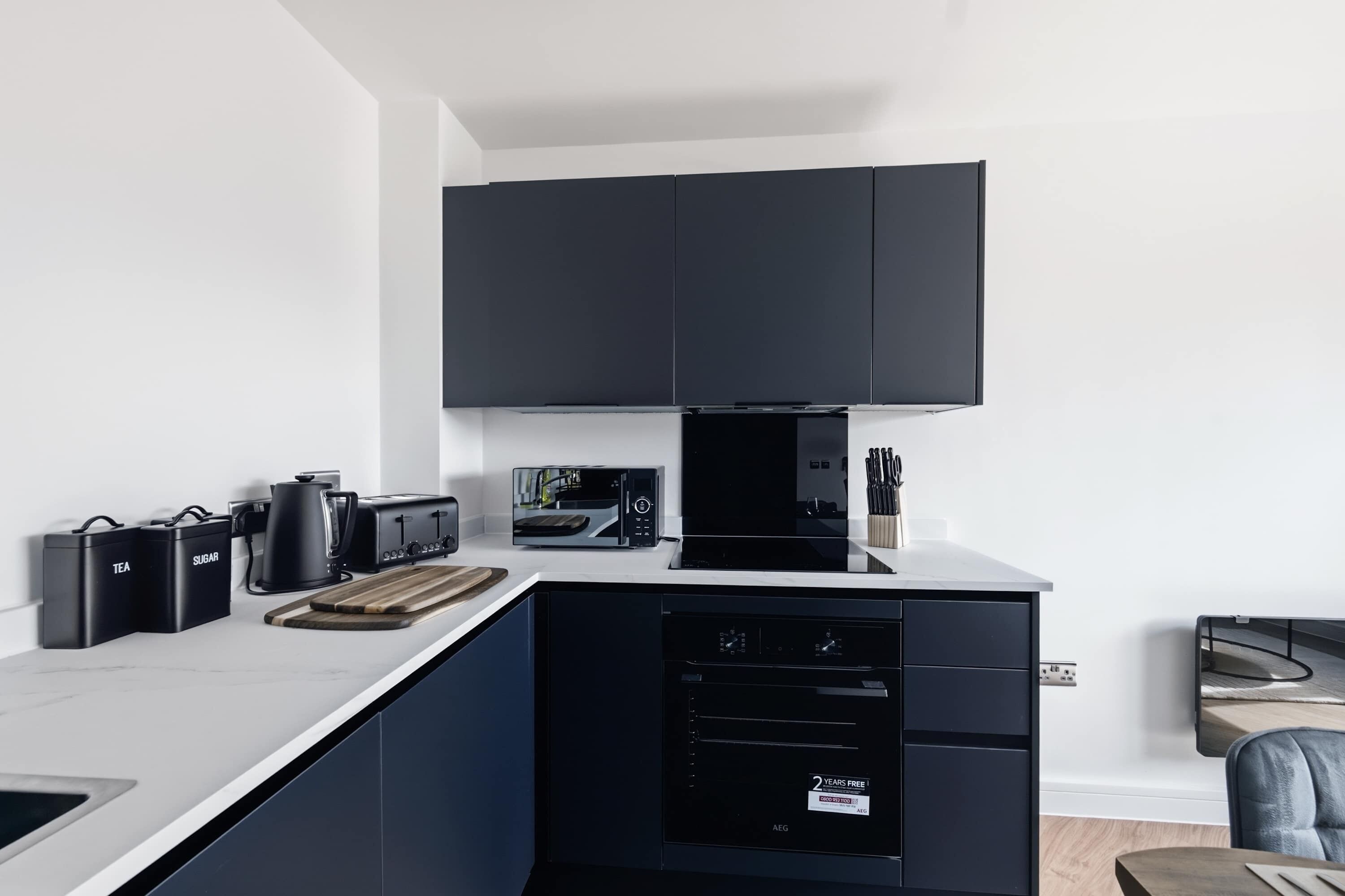 Uma cozinha moderna com lava-louças preta, micro-ondas e torradeira.