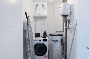 Ein Badezimmer mit Waschmaschine, Warmwasserbereiter und Dusche.