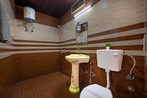 Une salle de bain équipée de toilettes, d’un lavabo, d’une douche et d’un chauffe-eau.