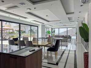 Una moderna hall d'albergo con una reception, un'area salotto e ampie finestre che offrono vista sull'esterno.
