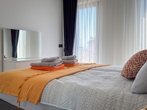 Une chambre d’hôtel avec un lit, une table de chevet, un miroir et une fenêtre avec des rideaux.