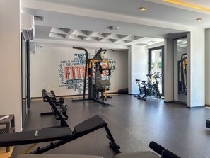 Une salle de sport équipée de matériel d’exercice, un mur orné de citations motivantes et une porte donnant sur l’extérieur.