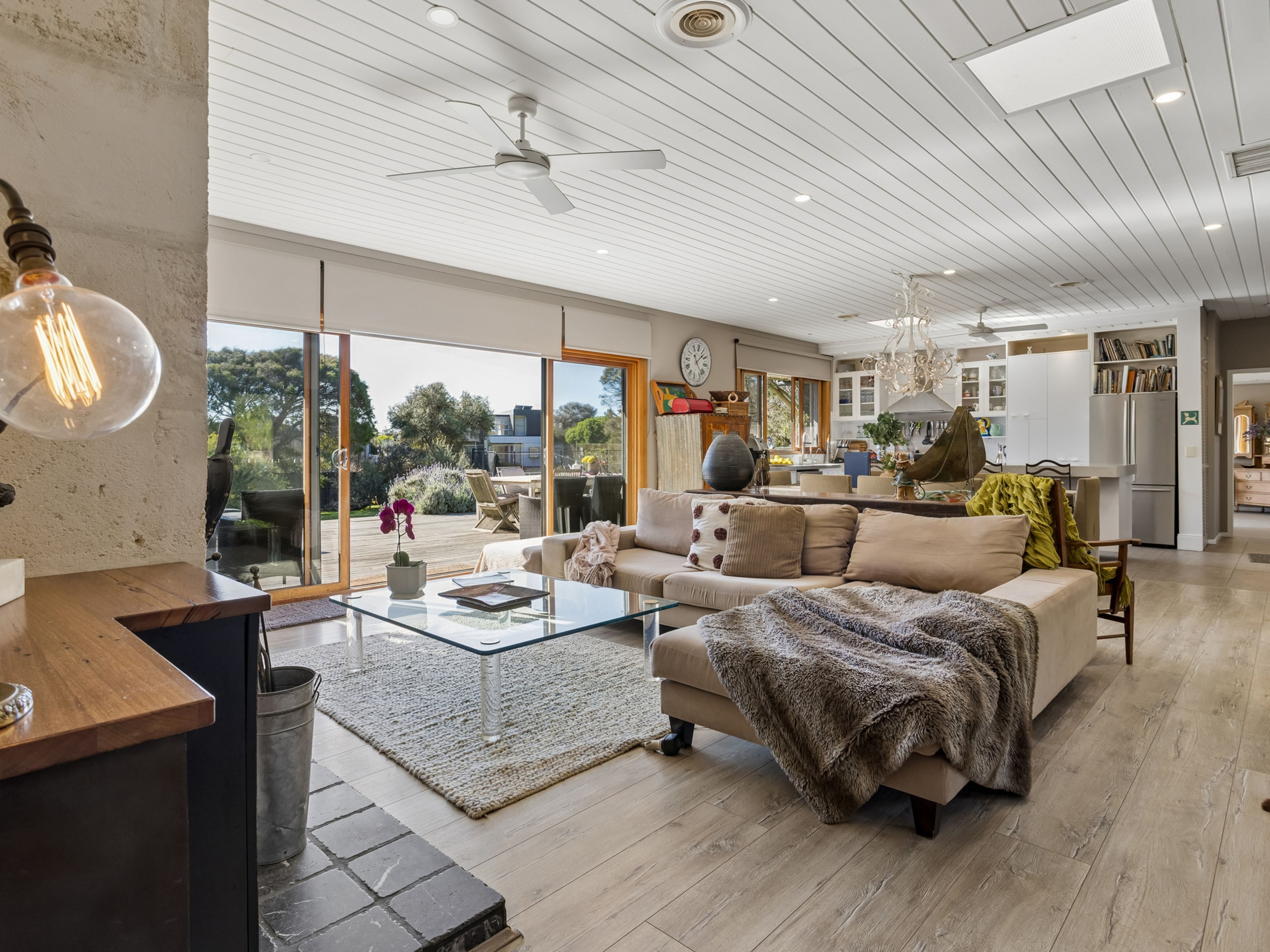 A spacious living area with a large sofa, a glass coffee table, and a view of the outdoors.