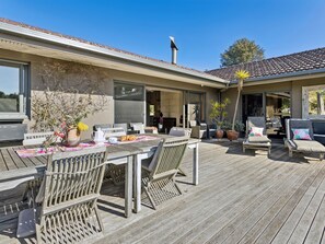 A wooden deck with outdoor furniture, including chairs and a table, and a potted plant. - Solhaven Sorrento Pool and Tennis Retreat (Sorrento)