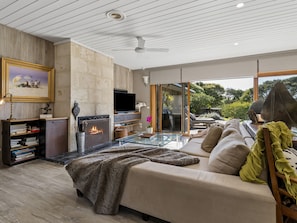 Ein modernes Wohnzimmer mit Kamin, Sofa und Glastisch.