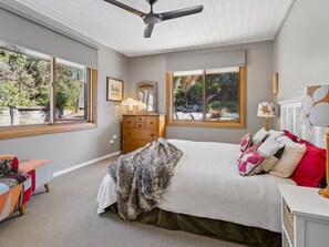 Ein Schlafzimmer mit Bett, Kommode und Fenstern.