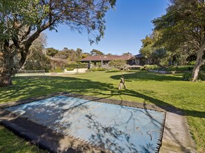 A backyard with a trampoline, a house, and a large tree. - Solhaven Sorrento Pool and Tennis Retreat (Sorrento)