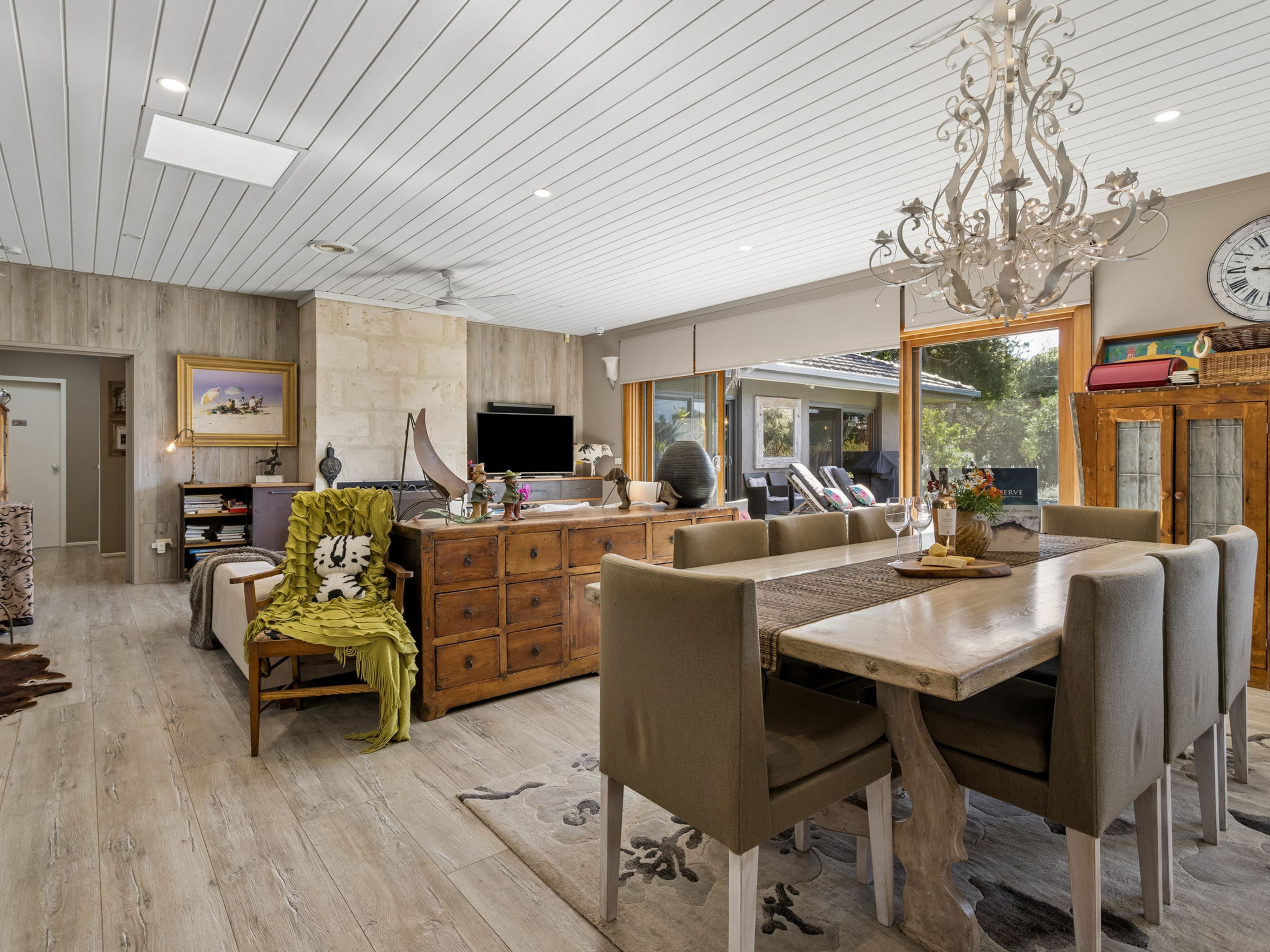 A spacious living area with a dining table, comfortable seating, a large mirror, and a chandelier.