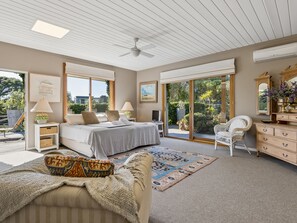 A bedroom with a bed, bedside tables, a chair, a dresser, and a large window. - Solhaven Sorrento Pool and Tennis Retreat (Sorrento)