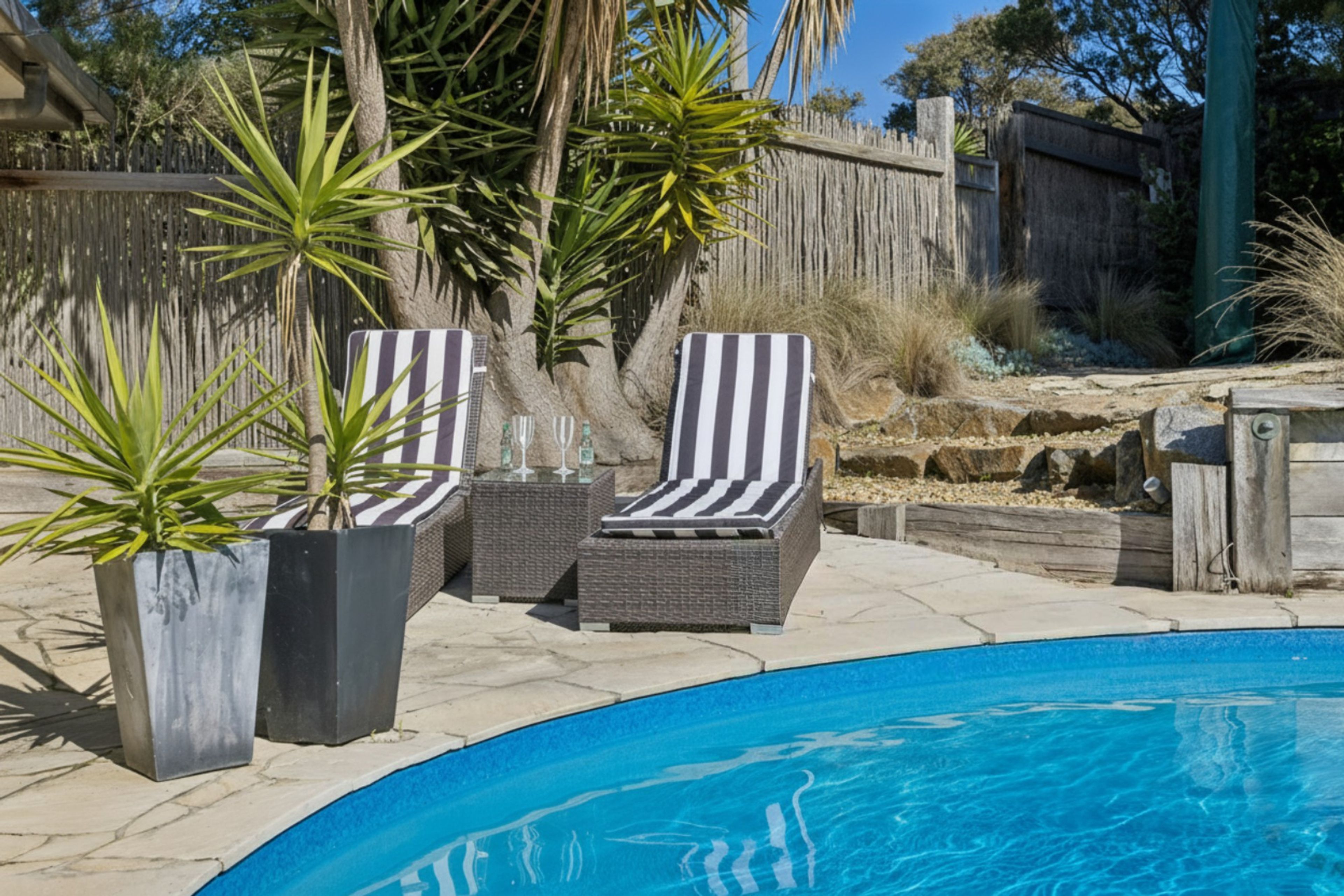 A swimming pool with lounge chairs and potted plants.