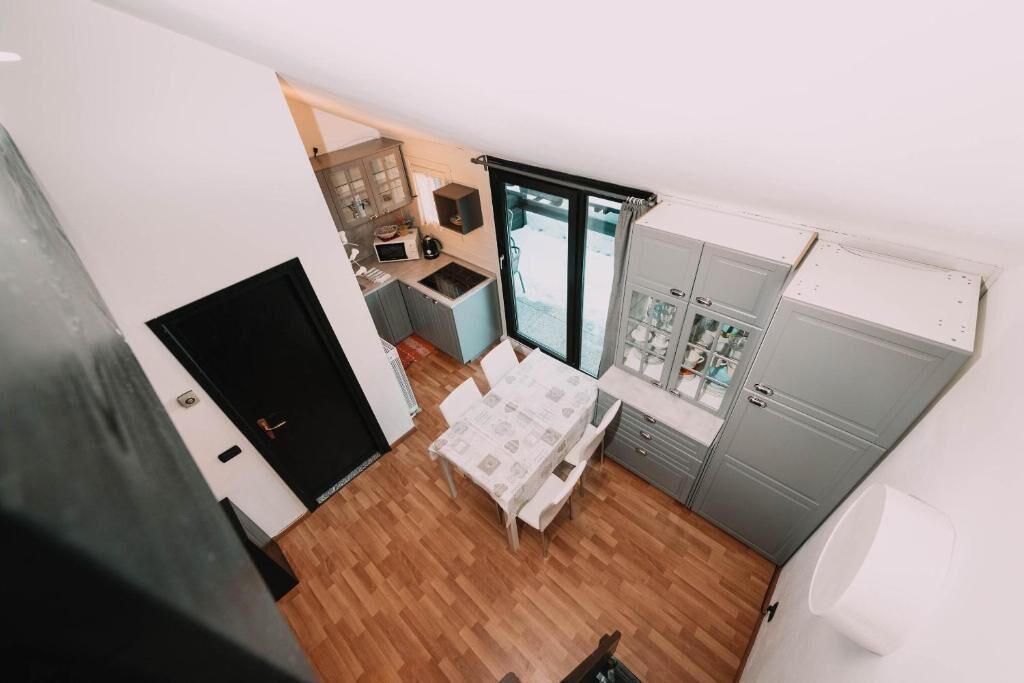 A compact kitchen with a dining area, a black door, and a window.