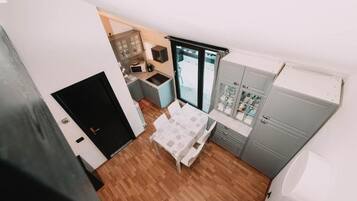 A compact kitchen with a dining area, a black door, and a window.