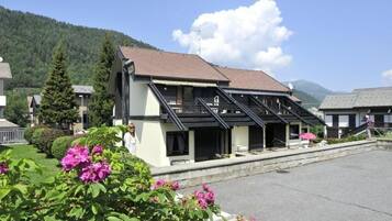 A hotel with a sloped roof, a covered outdoor seating area, and a view of a mountain.