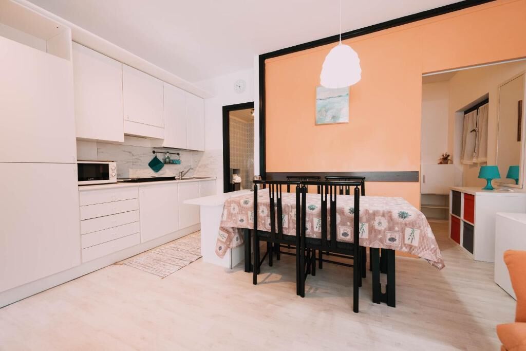 A compact kitchen with white cabinets, a microwave, and a dining area with a table and chairs.