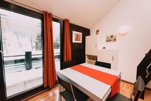 Quarto com cama, janela com cortinas, escrivaninha e cadeira.