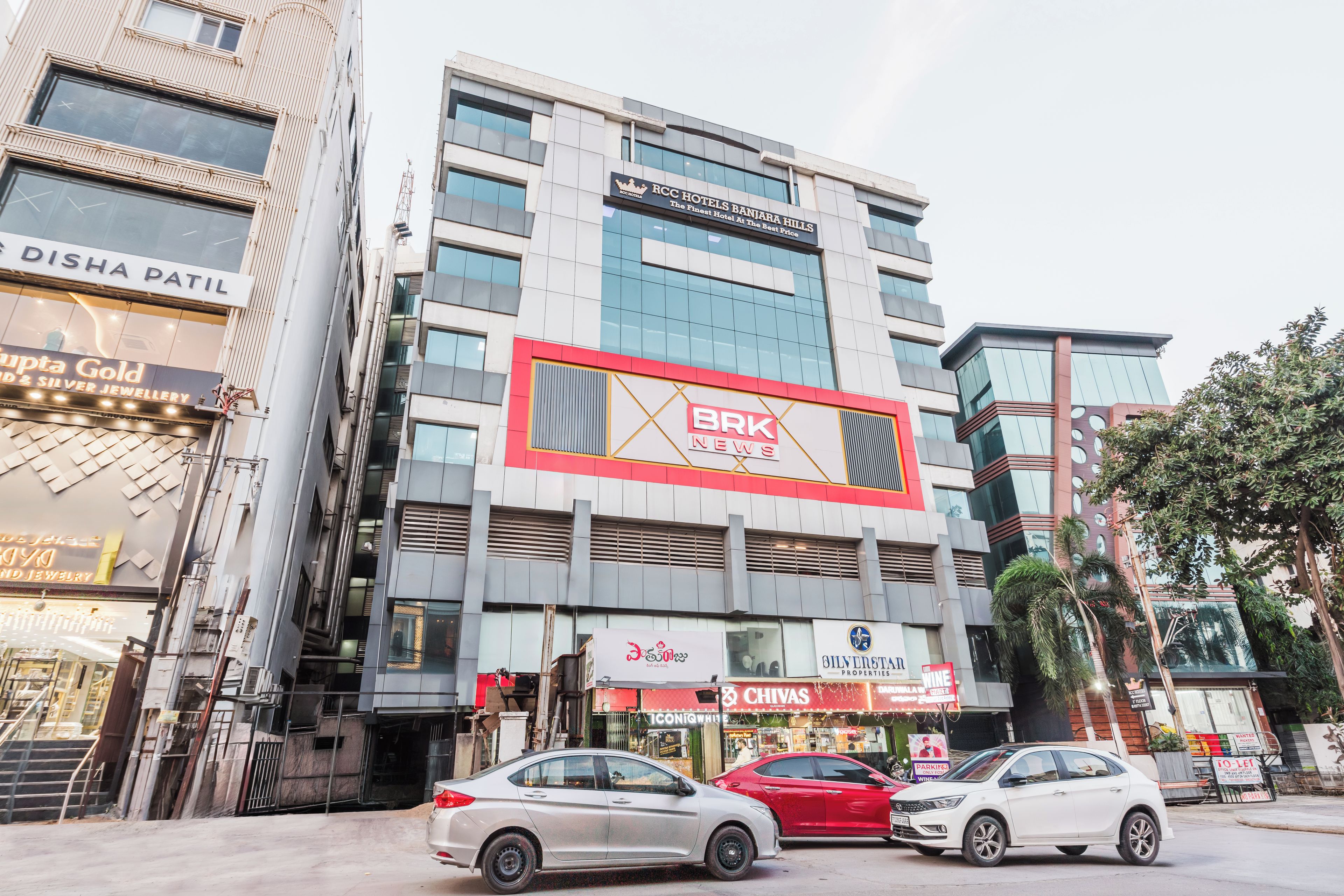 A multi-story building with commercial establishments on the ground floor, including a jewelry store and a news outlet.